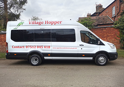 A white Ford Transit minibus Village Hopper parked by the roadside with a view from the side