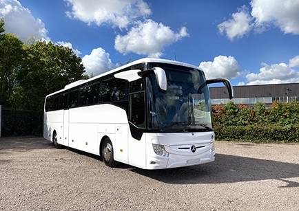 A white Mercedes-Benz coach parked outside