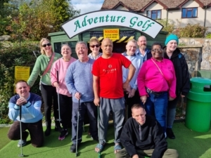 A group of people standing in front of an Adventure Golf sign