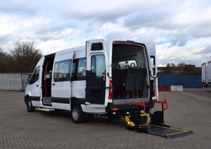 A white accessible vehicle parked up with its doors open and a ramp out