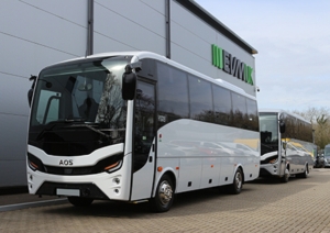 Two white Isuzu coaches parked up in front of a building