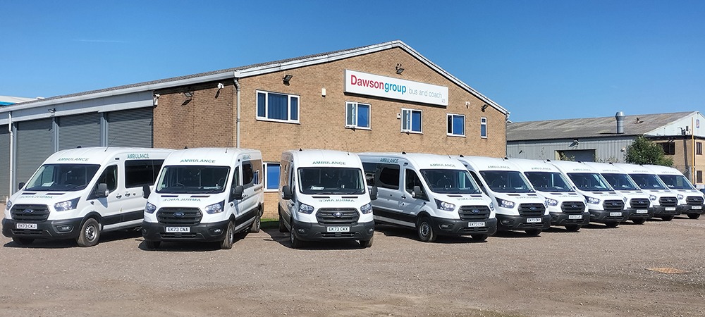 10 Patient Transfer Service vehicles lined up in front of Dawsongroup bus and coach